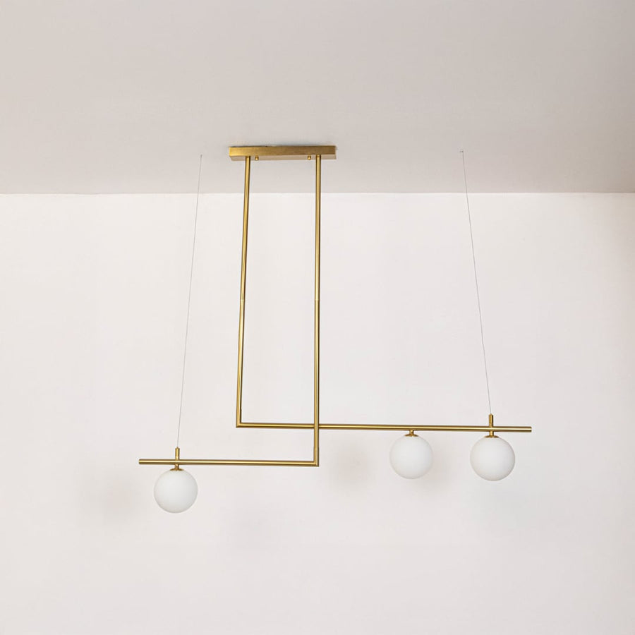 Gold pendant light with frosted glass globes and linear frame in off mode displayed on white background for decor view.