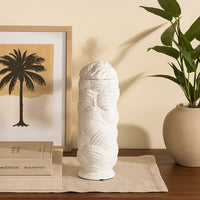 Tall white ceramic vase with sculptural textured detailing styled on a wooden console beside framed artwork and indoor plants for a cozy decor look.