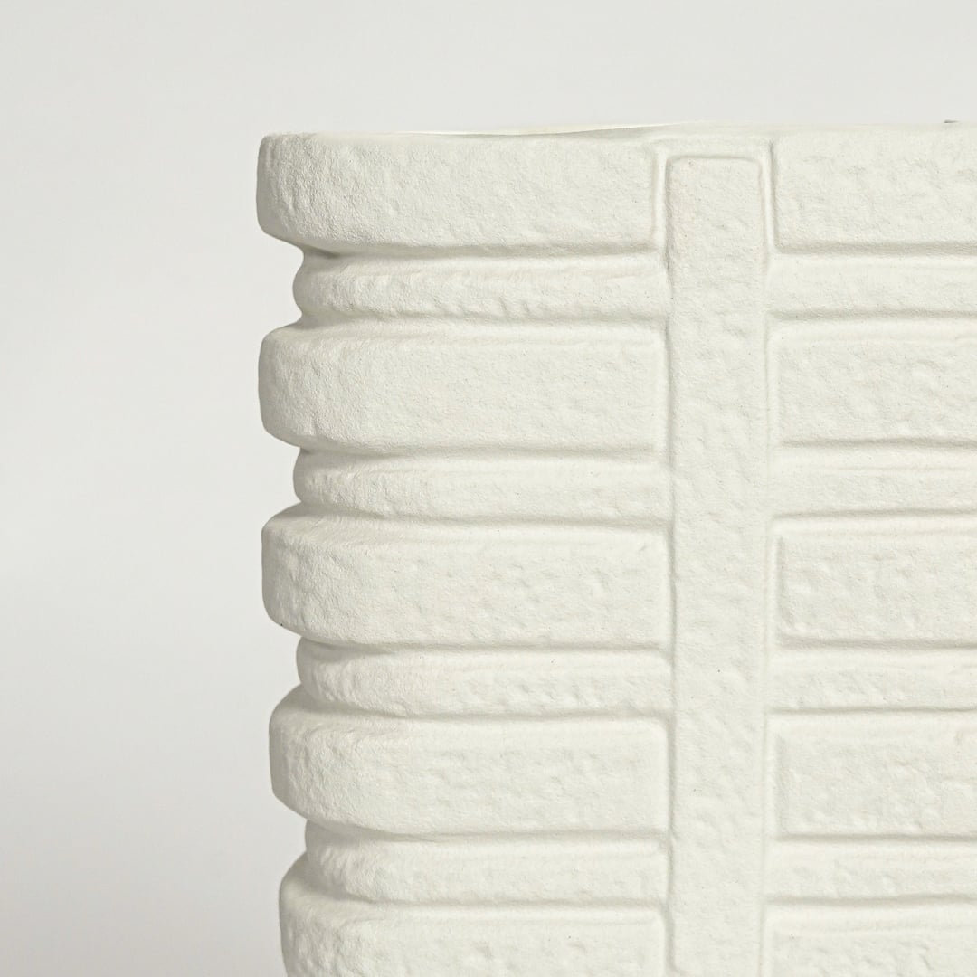 Close up view white ceramic vase showing layered ribbed texture sculpted vertical pattern modern decor accent.