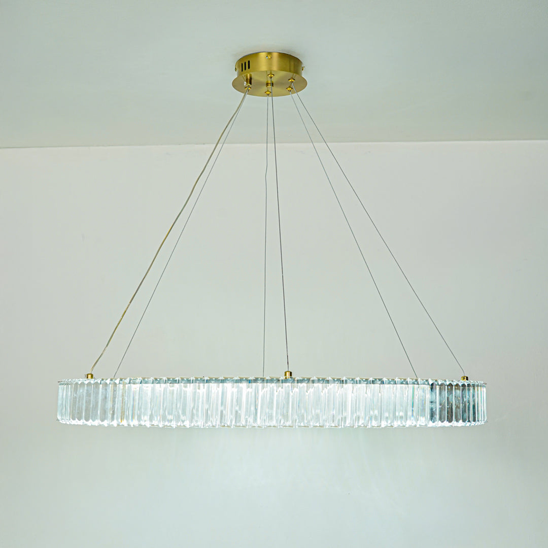 Elegant long crystal chandelier with transparent glass elements and gold finish suspended against clean ceiling background for premium modern decor.
