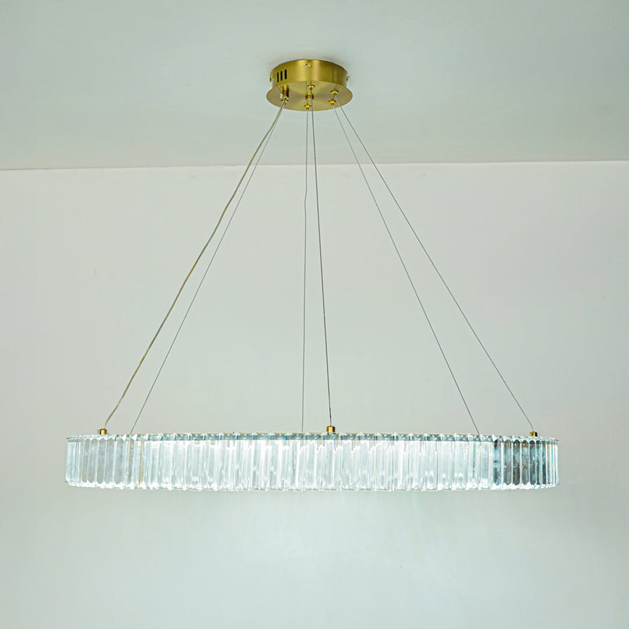 Elegant long crystal chandelier with transparent glass elements and gold finish suspended against clean ceiling background for premium modern decor.
