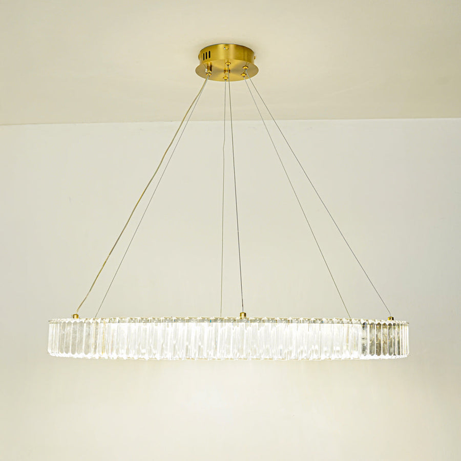 Contemporary linear crystal pendant light with gold metal frame suspended against clean white ceiling background ideal for modern dining or living space lighting.