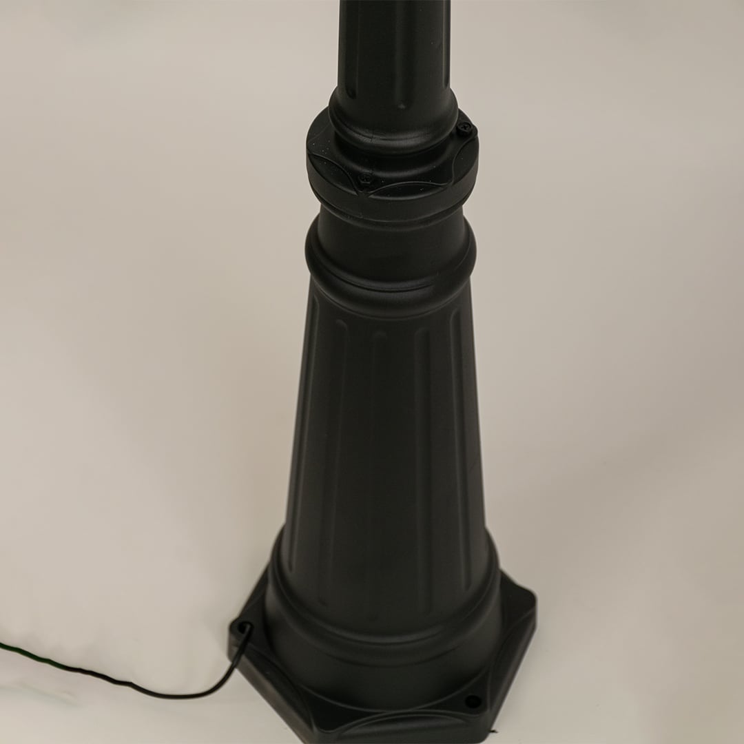 Closeup of black metal dual lantern lamp post showing ribbed glass and ornate curved arms perfect for enhancing garden driveway and home entrance Decor.