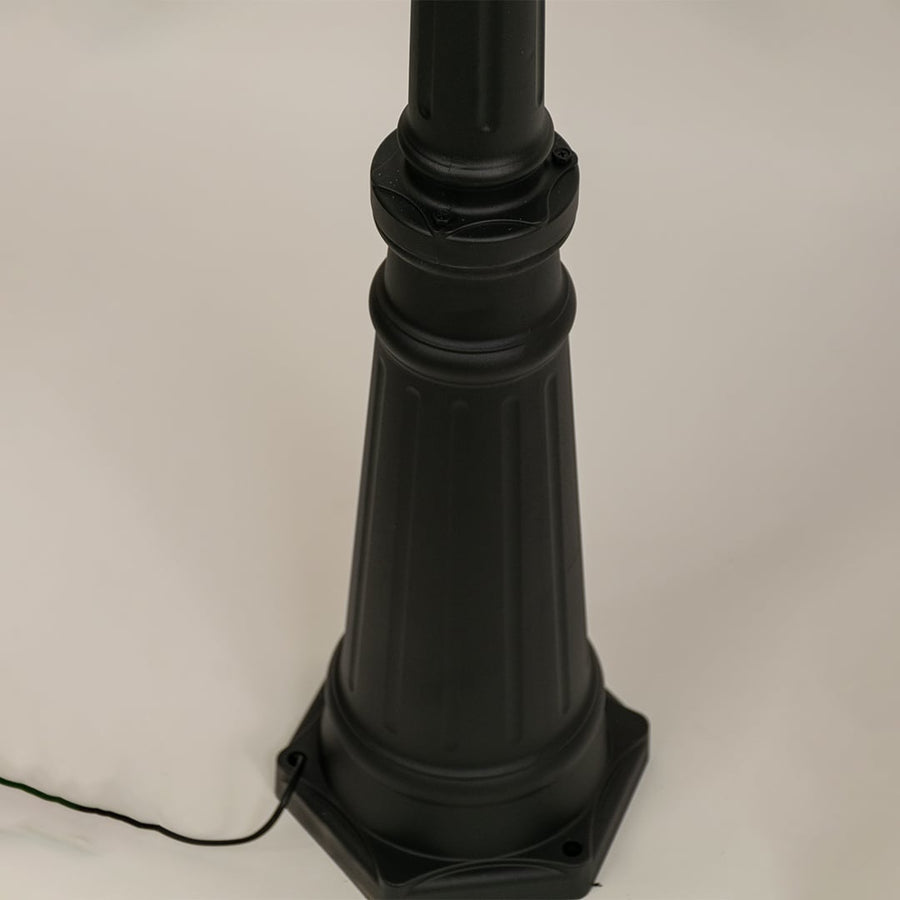 Closeup of black metal dual lantern lamp post showing ribbed glass and ornate curved arms perfect for enhancing garden driveway and home entrance Decor.