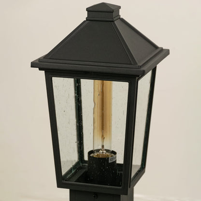 A detailed closeup of the outdoor post light showing the textured clear glass and metal frame with visible bulb socket and refined craftsmanship.