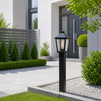 Classic black aluminum tapered glass pillar post lantern on gravel walkway for modern residential home entryway lighting.