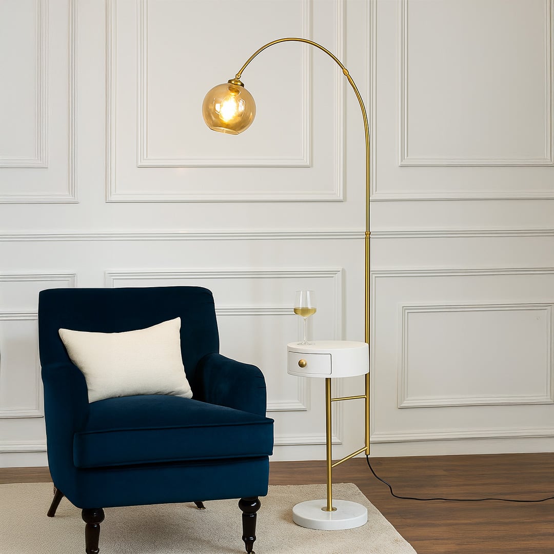 Stylish floor lamp next to a velvet chair in a sophisticated living room with light-colored walls showing soft lighting from the globe shade.