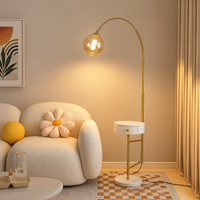 Modern gold arc floor lamp with globe glass shade beside accent chair creating soft ambient living room lighting.