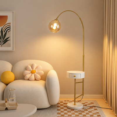Modern gold arc floor lamp with globe glass shade beside accent chair creating soft ambient living room lighting.