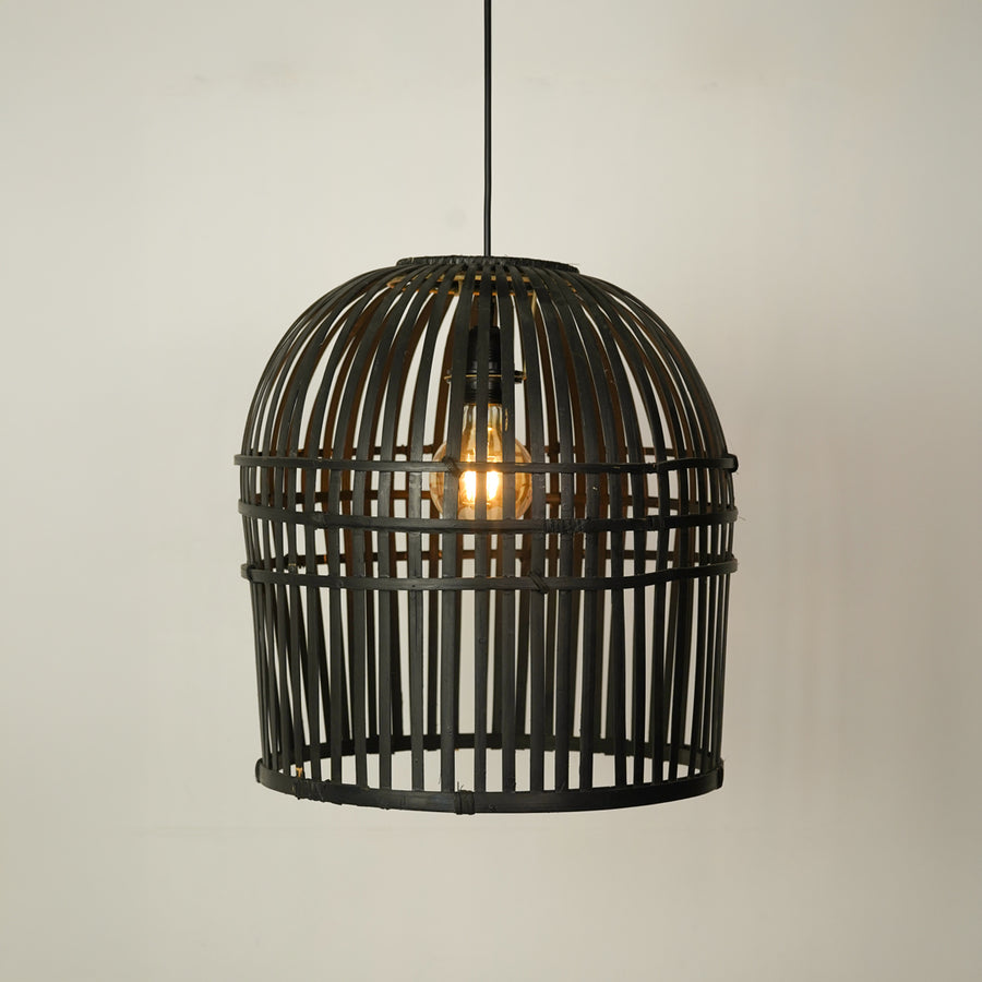A black metal birdcage pendant light hanging from a black cord against a plain off-white wall, with a glowing warm light bulb visible inside.