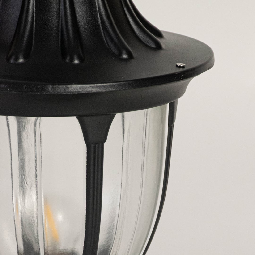 Closeup of decorative outdoor black pillar lamp with dome top and transparent glass panels highlighting classic design.