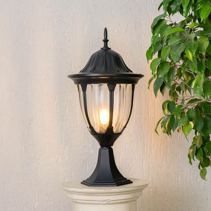 Elegant outdoor black pillar lamp glowing warmly with LED bulb inside clear glass panels perfect for patio driveway and gate.