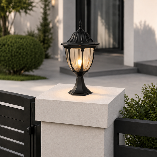 Traditional black metal textured glass globe post lantern on white concrete gate post for residential yard entryway decor.