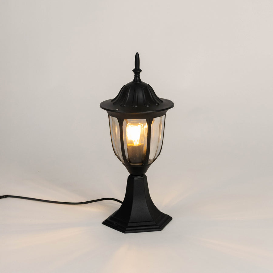 Vintage black outdoor gate light with warm glowing bulb for elegant exterior decor styling use.
