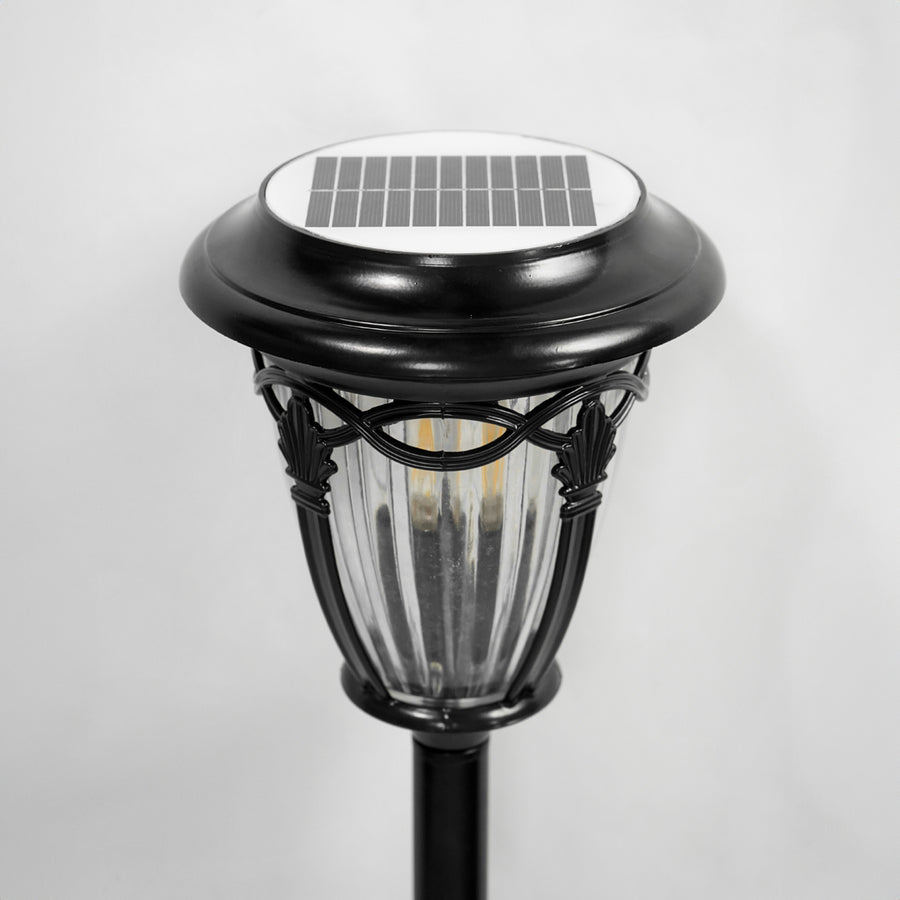 Closeup of black metal solar pathway light with integrated LED top for garden walkway and landscape lighting.