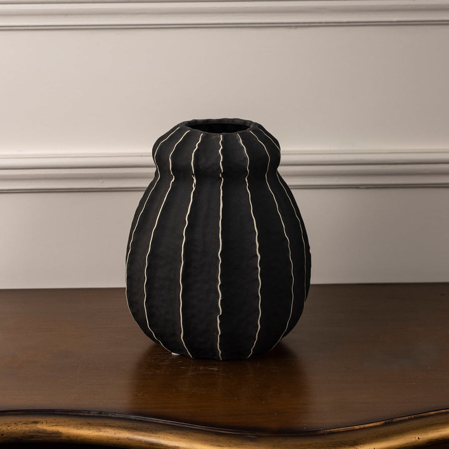Noir black ceramic vase displayed on a white background showcasing its handcrafted vertical stripe pattern and organic rounded shape.