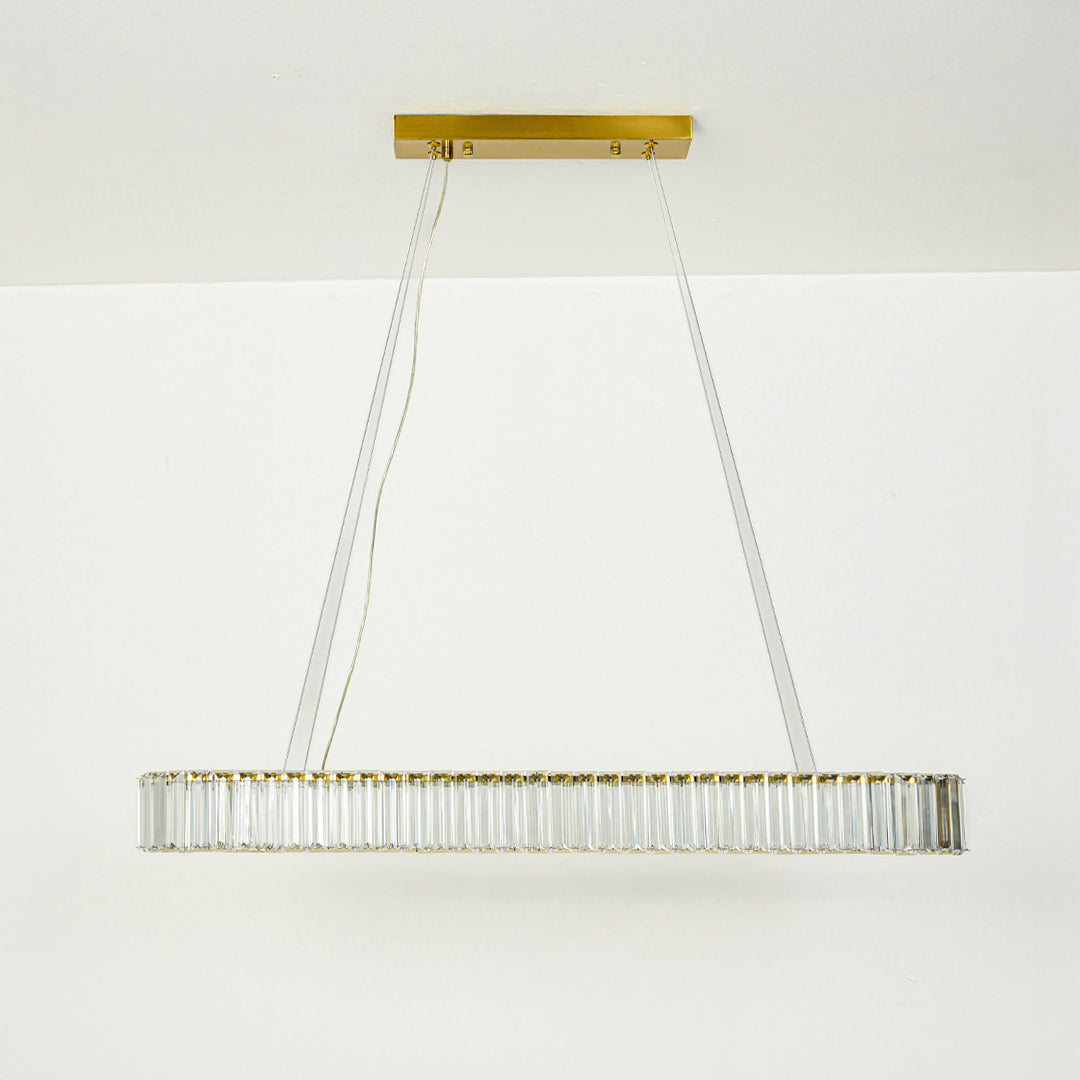 Modern crystal linear chandelier with gold metal frame suspended by cables against clean white ceiling background ideal for luxury dining lighting.