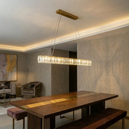 Contemporary linear pendant light with gold metal finish suspended above dining table in modern interior setting with warm ambient lighting.
