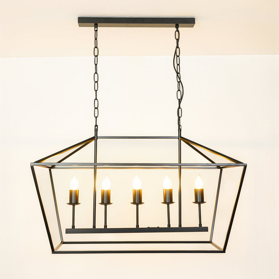 Contemporary black metal linear pendant light with exposed bulbs in geometric cage design hanging against neutral wall background for modern decor.