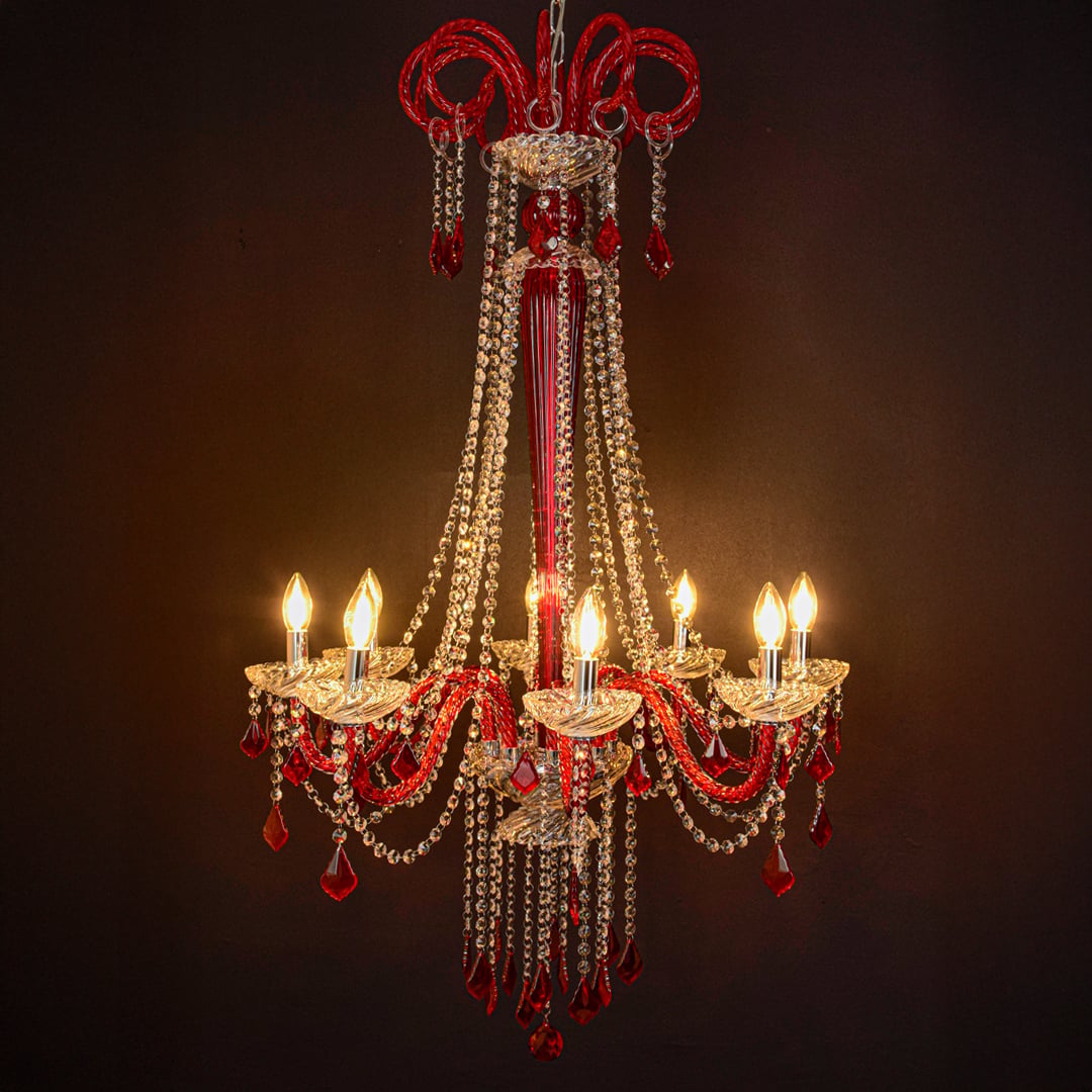 Red and clear crystal chandelier glowing softly on black background creating a dramatic luxury ceiling feature.