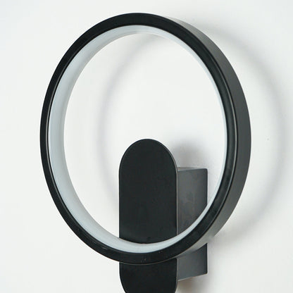 Close view of black metal wall sconce with circular LED ring and oval backplate on clean white wall background showcasing contemporary lighting design.