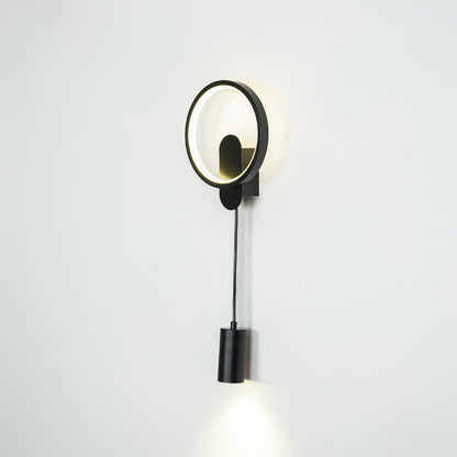 Contemporary gold wall sconce with LED ring and black spotlight mounted on neutral wall background ideal for modern bedroom or hallway lighting.

