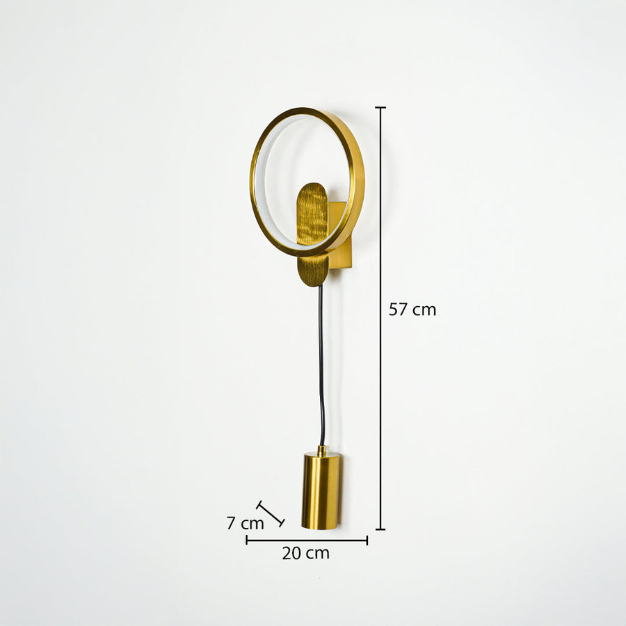 Gold wall light with circular frame and hanging cylindrical pendant on neutral wall background 57 cm height 20 cm width 7 cm depth ideal for modern bedroom lighting.