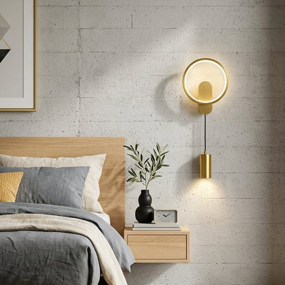 Gold wall light with circular ring and white glass shade mounted beside bed on neutral wall background ideal for modern bedroom decor lighting.
