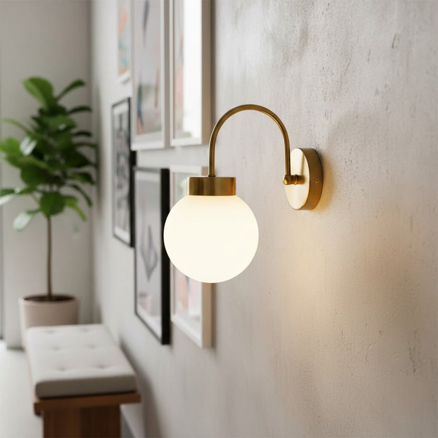 Modern gold metal wall light with white glass globe for elegant bedroom and luxury decor styling spaces.

