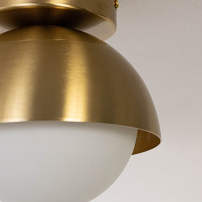 Closeup of modern ceiling light in brushed gold finish with frosted glass shade for home decor lighting.