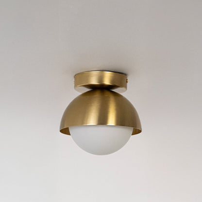 Ceiling light with gold dome shade and frosted white glass globe shown switched off on white background.