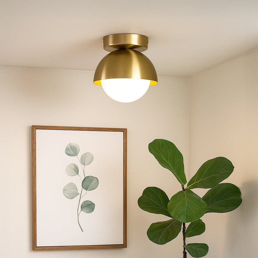 Ceiling light in gold finish with frosted globe shade styled in modern living space for home interior lighting.