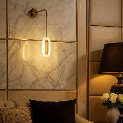 Gold metal wall mounted pendant light glowing warmly on marble accent wall beside bed adding luxury ambient lighting to modern bedroom decor.