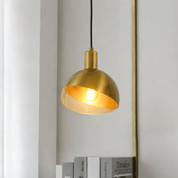 Brushed gold metal pendant light with warm glow hanging beautifully in modern interior setting.
