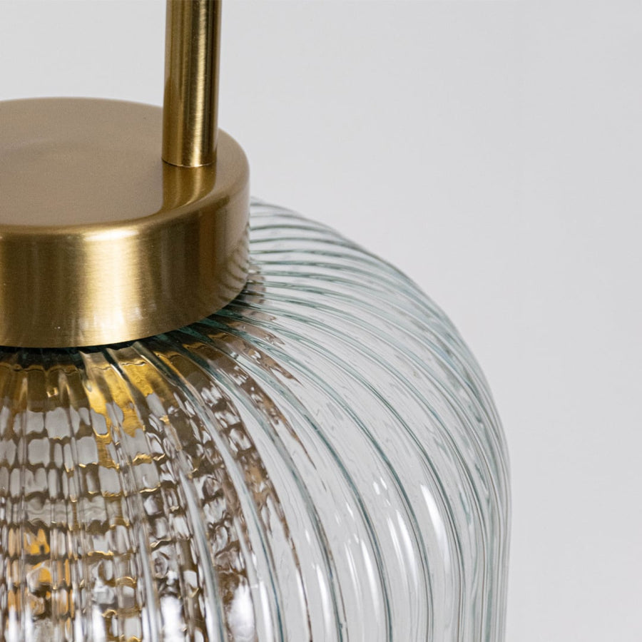 Closeup of clear ribbed glass and gold metal pendant light highlighting premium texture and finish.