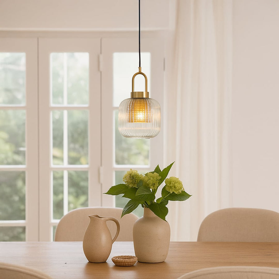 Clear ribbed glass and gold metal pendant light adding warm charm to bright dining room interiors.
