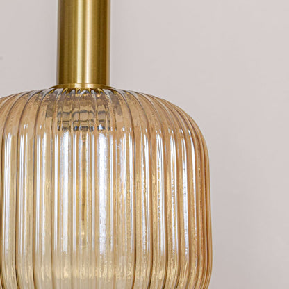 Closeup of amber ribbed glass pendant light showing vertical texture gold metal top and premium decorative lighting finish.