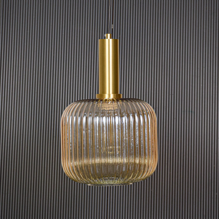 Gold metal and ribbed glass pendant light switched off displayed on black background showing clean shape and modern style.