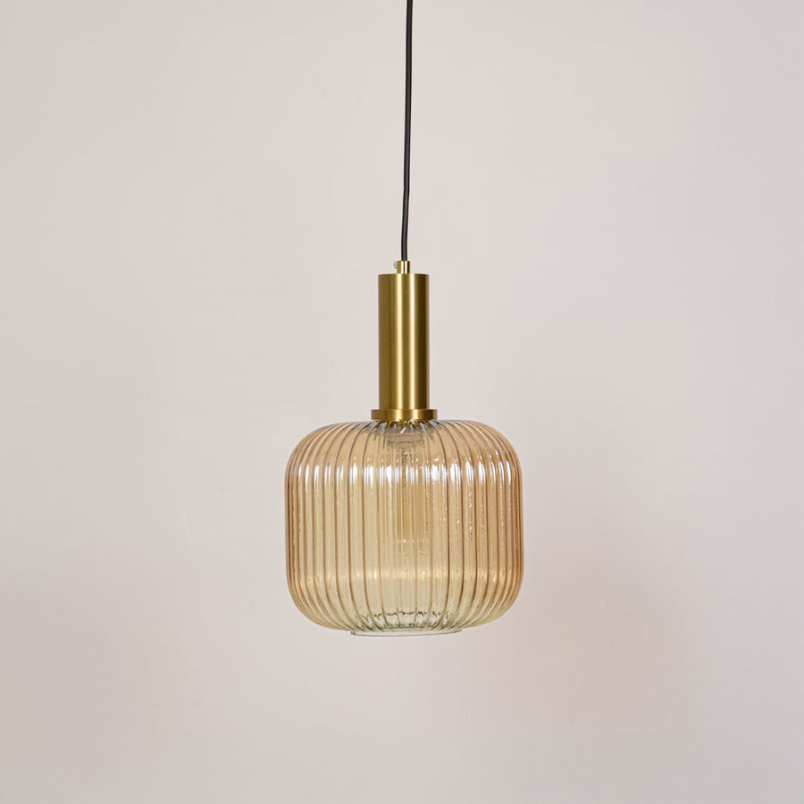 Modern gold metal and ribbed glass pendant light switched off on white background designed for ceiling mounted decor.