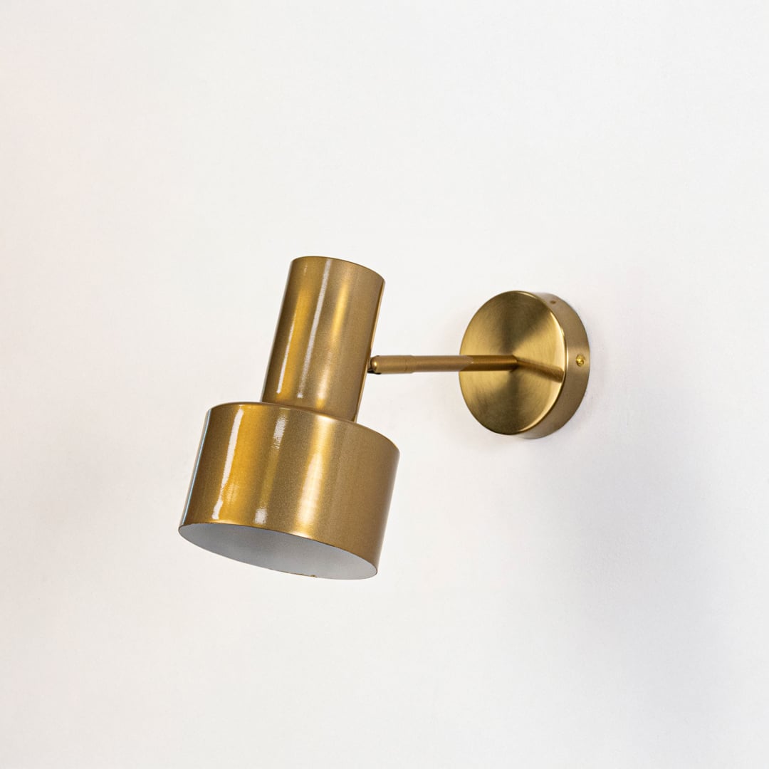 A gold wall light with a sleek cylindrical design displayed switched off against a plain white background highlighting its smooth metallic finish.
