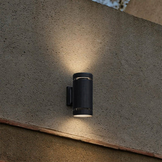 Black metal outdoor wall light lifestyle image with warm upward downward glow for modern exterior decor.