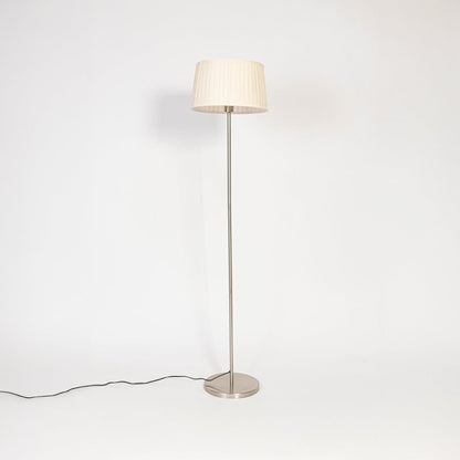 Steel floor lamp with cream pleated shade turned off on plain white background stylish decorative lighting.