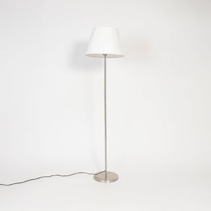 Steel floor lamp with white fabric pleated shade turned off on white background decorative home accent.