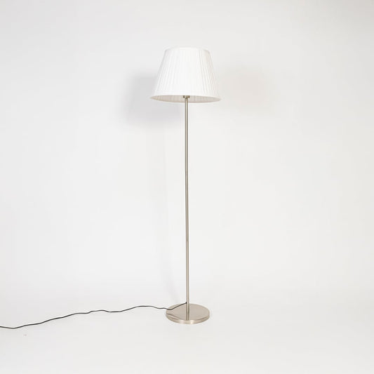 Steel floor lamp with white fabric pleated shade turned off on white background decorative home accent.
