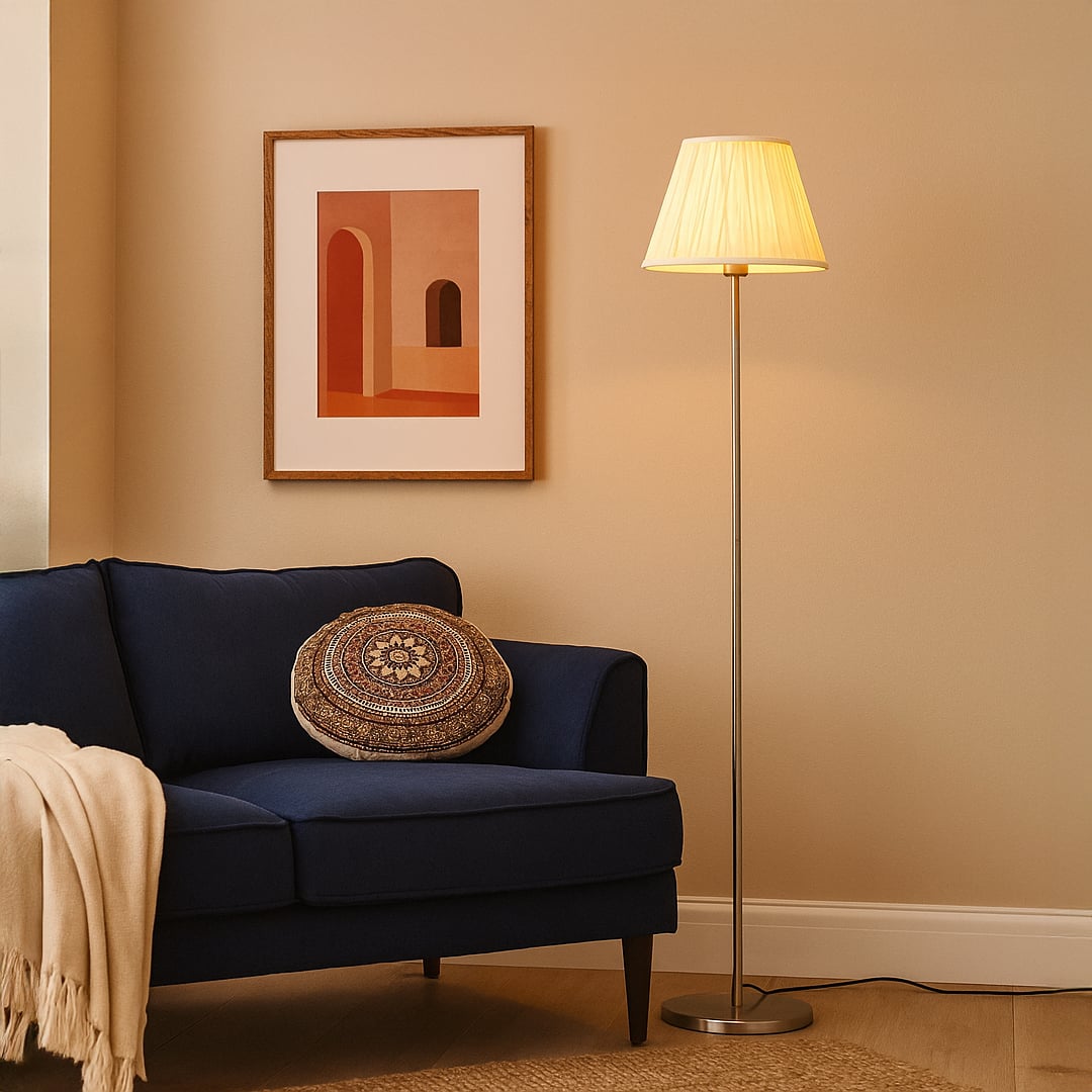 Steel floor lamp with pleated cream shade beside navy sofa and wall art in modern living room lighting decor.