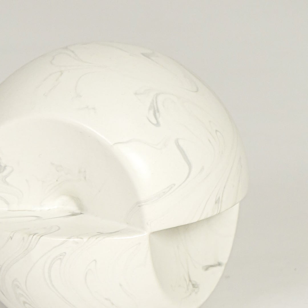 Table decor object in white marble finish with smooth rounded form and subtle grey veining shown in close up highlighting its sculptural modern design and matte texture