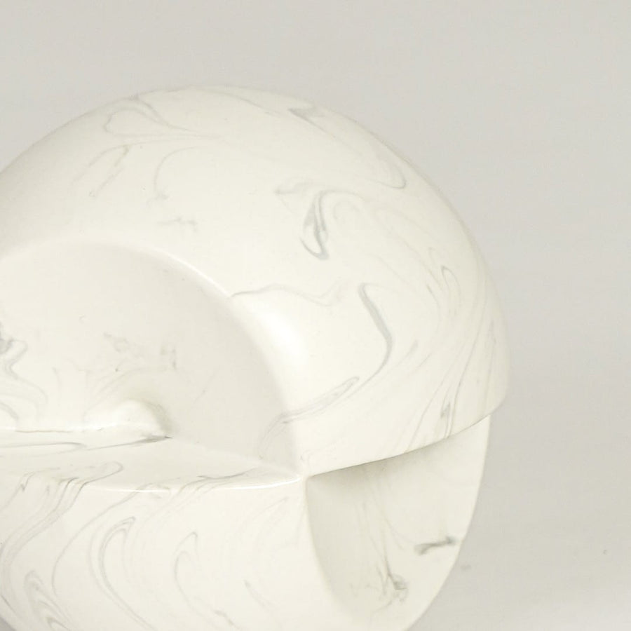 Table decor object in white marble finish with smooth rounded form and subtle grey veining shown in close up highlighting its sculptural modern design and matte texture