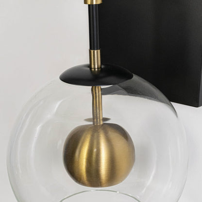 Closeup image of black metal wall light with transparent glass globe and gold accent for modern interior decor.