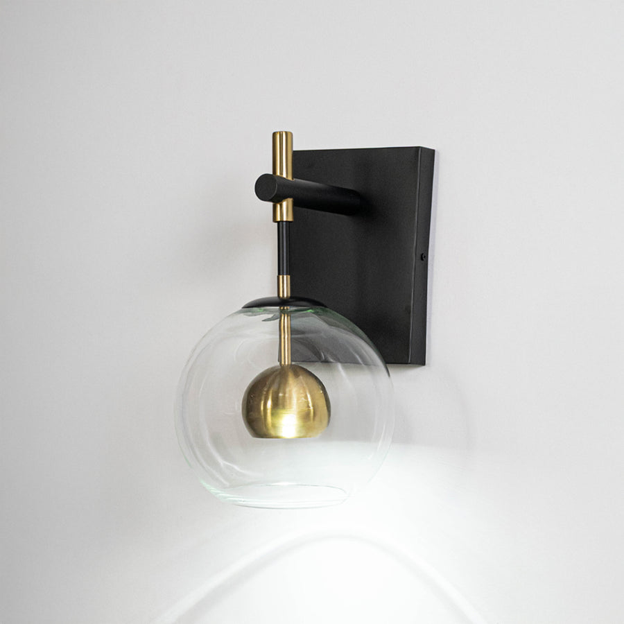 Contemporary wall light in black metal finish with glass globe shade for bedroom or living decor lighting placement white background.
