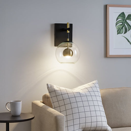 Modern black metal wall light lifestyle image with glass globe shade for cozy living room ambient lighting.